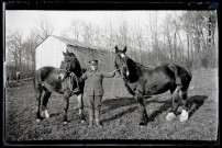 Portraits du Corps des forestiers canadiens et autres troupes : militaire tenant deux chevaux devant un baraquement en bois.