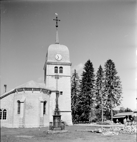 Vue extérieure du clocher et du chœur avec une croix au premier plan.