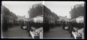 Etals d'un marché dans une rue de Paray-le-Monial, en arrière-plan une porte indique "Vive le Christ qui aime les Francs".