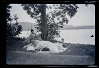 Trois femmes allongées dans l'herbe au bord d'un lac.
