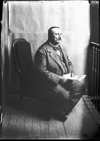 Un homme assis sur un fauteuil avec son journal.