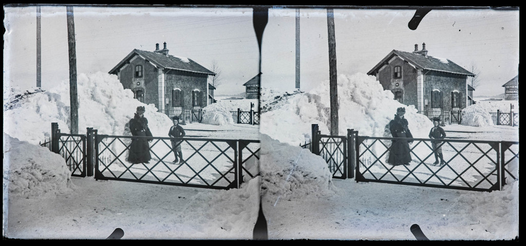 Femme et enfant au pied d'un tas de neige, à côté d'un passage à niveau.