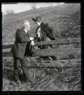 Elisée Coutemoine tenant la main d'une dame âgée au dessus d'une barrière en bois.