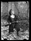 Portrait d'un jeune garçon avec une carabine, vue de profil.