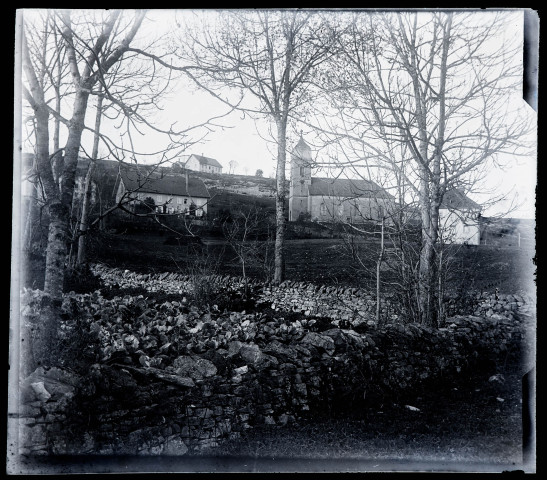 Eglise et maisons éparses vues à travers les arbres.