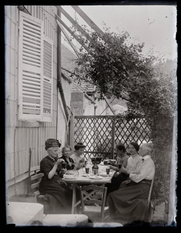 Six femmes attablés dans le jardin d'une maison avec une boisson, dont Anne Coutemoine (à gauche) et sa sœur Agathe (à droite).