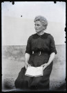 Portrait d'une femme assise, un livre ouvert entre les mains.