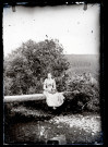 Agathe Coutemoine assise sur un tronc d'arbre servant de passerelle au dessus d'un cours d'eau.