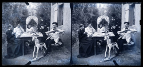 Trois femmes et trois hommes attablés avec une boisson dans un jardin devant une maison, un homme lit le journal "Le petit parisien".