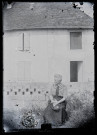 Agathe Coutemoine assise devant la maison Coutemoine à Vers-en-Montagne, un chat sur les genoux.