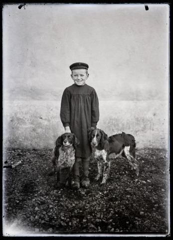 Portrait du jeune berger Louis Jouhant tenant deux chiens de chasse.