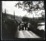 Trois femmes et un homme sur une route près d'un cours d'eau. De gauche à droite : Mathilde Coutemoine, Emilie Vuillaume, Maurice de Pagnoz et Agathe Coutemoine (avec un sac devant contenir un appareil photographique).