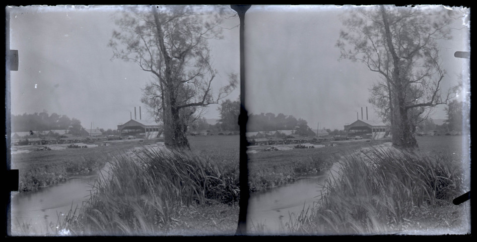 Scierie et baraquements au bord d'un cours d'eau.