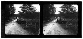Entrée du village d'Ardon, une femme près d'une charrette et de grumes de bois sur une route passant sous un pont de chemin de fer.