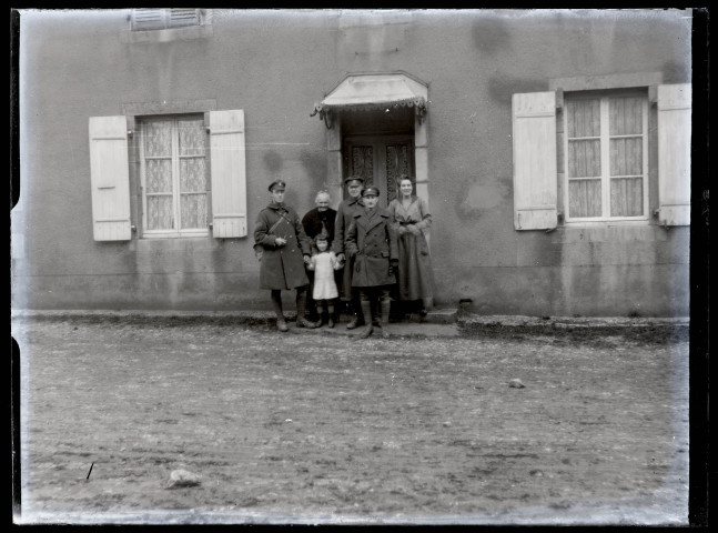 Famille avec trois militaires canadiens devant une habitation.