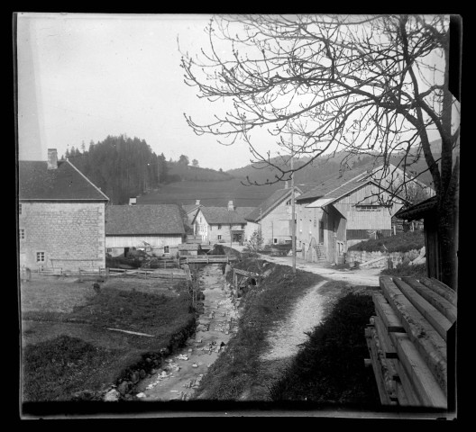 Rue, maisons et cours d'eau à Les Gras.