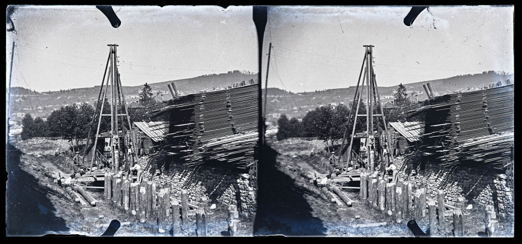 Hommes sur un chantier de construction, près d'empilements de planches.