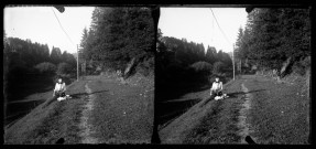 Emilie Vuillaume assise dans l'herbe au bord d'un chemin, un bouquet de fleurs dans la main.