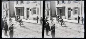 Course cycliste traversant un village, des spectateurs sur le trottoir.