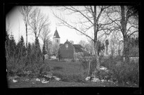 Eglise Saint-Laurent et presbytère à Vers-en-Montagne, vue prise entre les arbres.