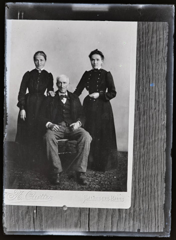 Portrait d'un homme âgé assis entouré de deux femmes debout, reproduction d'un cliché de A. Cartier, photographe à Salins-les-Bains.