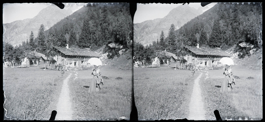 Femme à l'ombrelle près de chalets de montagne.