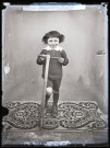Portrait d'un petit garçon debout, un pied sur une trottinette.