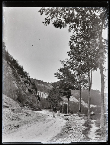 Deux ouvriers sur une route, un viaduc au loin.