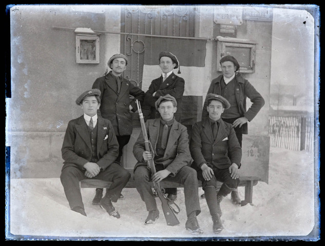 Portrait de groupe des conscrits des classes 19 et 20 de Vers-en-Montagne, dans la neige : Auguste Darbon, Georges Epailly et Noël Duboz (debout, de gauche à droite), Maurice Putod, Henri Vuiller et un jeune homme non identifié (assis, de gauche à droite).