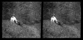 Emilie Vuillaume assise dans l'herbe, au bord d'un bois, avec son caniche Coquette.