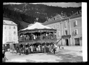 Enfants et adultes au carrousel, sur une place de Morez.