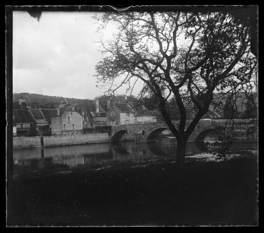 Maisons près d'un pont enjambant la Loue à Port-Lesney, un arbre au premier plan.