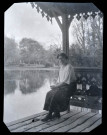 Jeune femme assise au bord d'un étang.