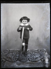 Portrait d'un petit garçon debout, un pied sur une trottinette.