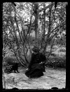 Emilie Vuillaume jouant avec un chat noir dans un jardin.