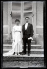 Portrait d'un couple de mariés posant sur les marches d'un bâtiment.