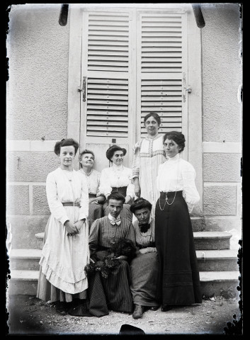 Sept femmes et un chien sur les marches du pensionnat de jeunes filles rue du Tatet à Vers-en-Montagne.