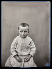 Portrait d'un petit enfant portant une blouse à carreaux, assis.