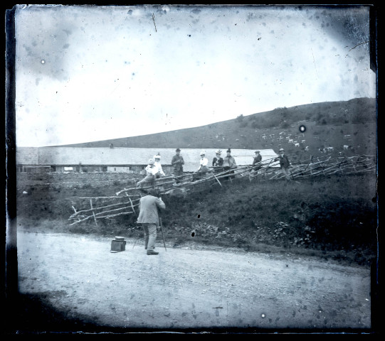 Homme photographiant un groupe près de la barrière d'une ferme.