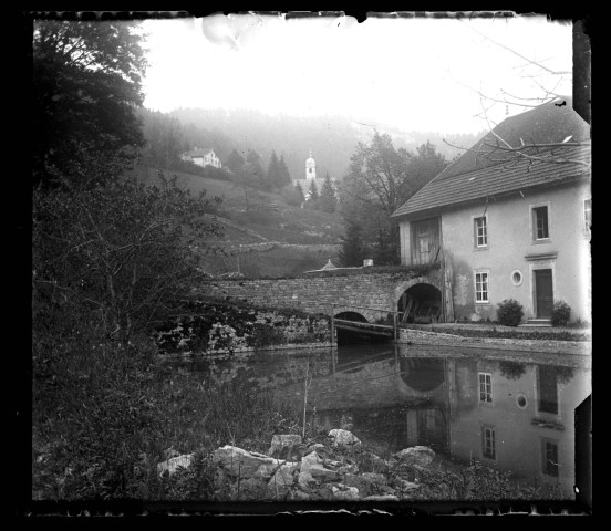 Maison au bord de l'eau, un clocher au loin.