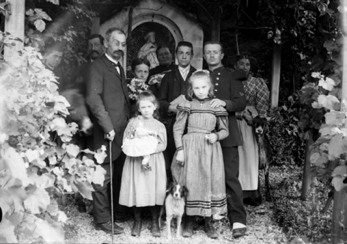 Six adultes et quatre enfants devant un oratoire