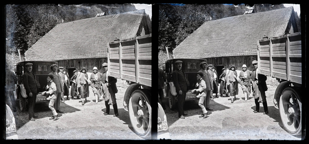 Groupe devant un bâtiment, entre une automobile et un camion.