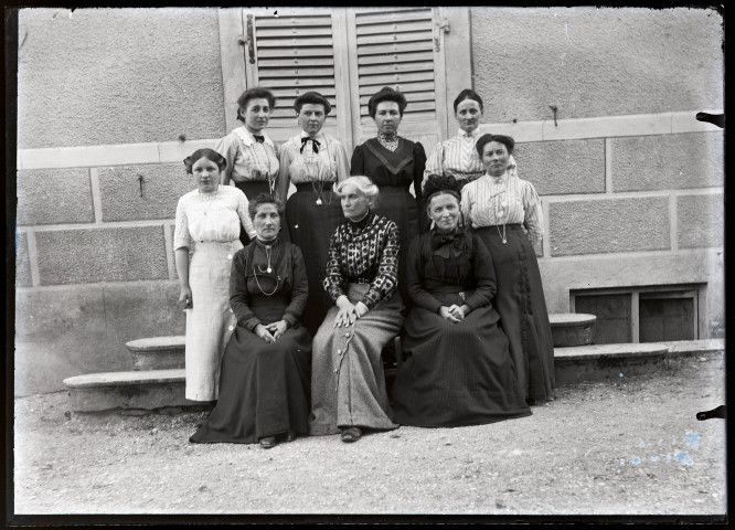 Neuf femmes sur les marches du pensionnat de jeunes filles rue du Tatet à Vers-en-Montagne, Agathe Coutemoine assise au centre du premier rang.