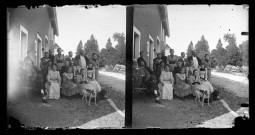 Groupe d'adultes et d'enfants avec deux chiens devant une maison. Abel Coutemoine assis à l'extrême gauche, sur le banc.