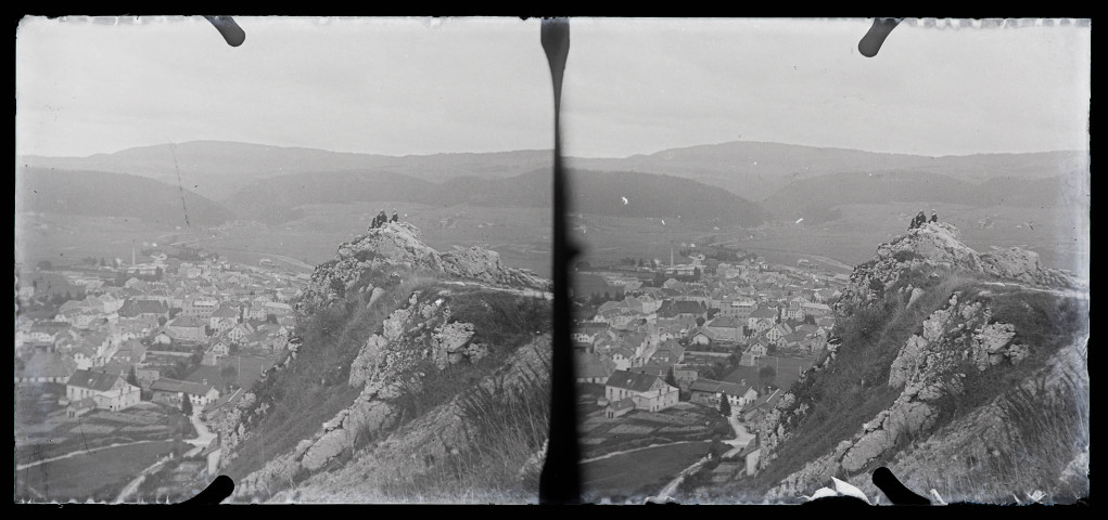 Un homme et un jeune garçon assis sur une roche surplombant un village.