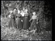 Six femmes (dont Mathilde Coutemoine, 2e à partir de la droite), un prêtre et un militaire posent dans la nature, le militaire porte le rabat et le chapeau du prêtre.