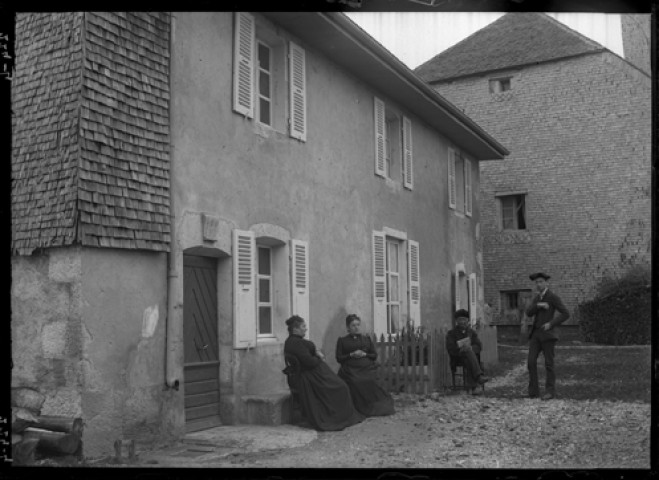 Quatre personnes. Quatre personnes posant devant une maison