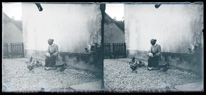 Femme entourée de volailles assise devant la maison Coutemoine à Vers-en-Montagne, une poule mange sur ses genoux.