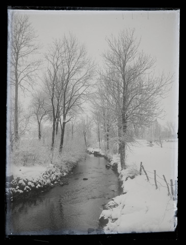 Paysage de neige traversé par un cours d'eau.