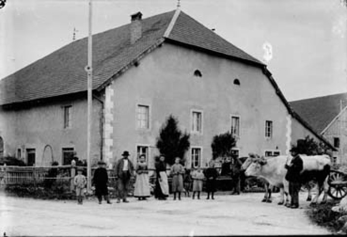 Personnes avec des boeufs devant une maison